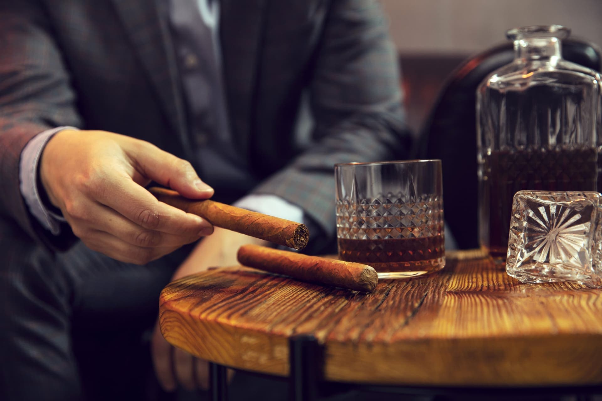 A cigar and crystal whiskey glass beside a decanter at a private event