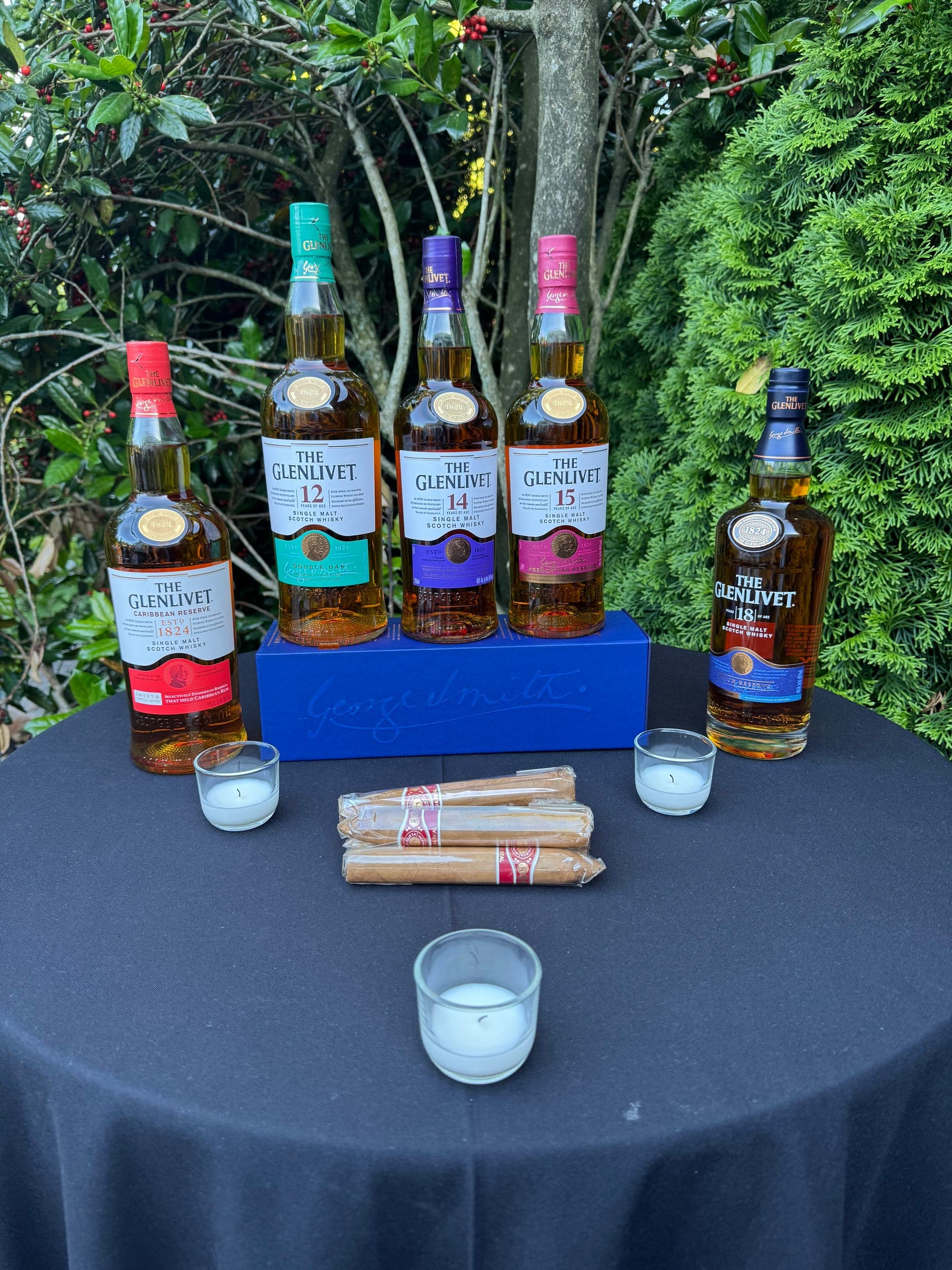 A flight of aged whiskies paired with hand-selected cigars in a garden setting